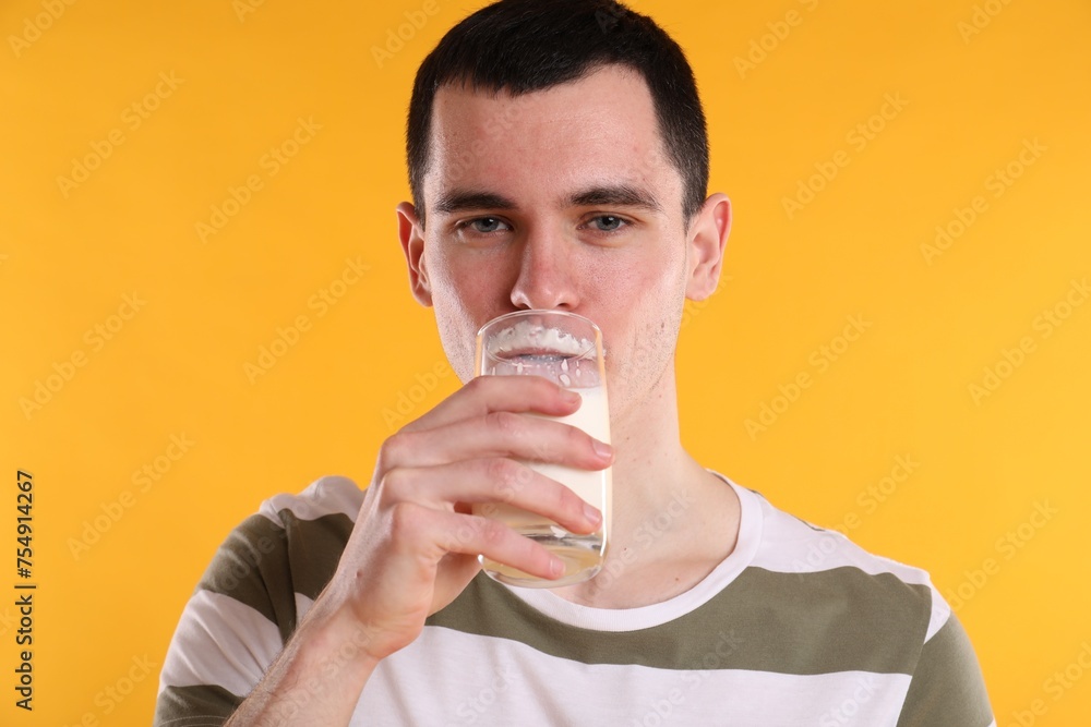 Milk mustache left after dairy product. Man drinking milk on orange background Milk mustache left after dairy product. Man drinking milk on orange background