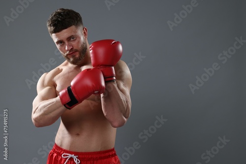 Man putting on boxing gloves against grey background. Space for text © New Africa