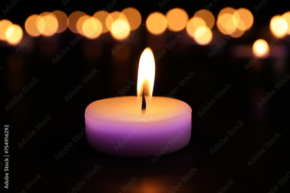 Burning violet candle on dark surface. Funeral attributes Burning violet candle on dark surface. Funeral attributes