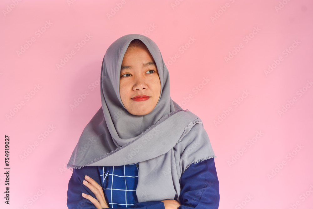 Young Asian woman standing very confidently facing the camera. Indonesian woman in blue shirt with gray hijab Young Asian woman standing very confidently facing the camera. Indonesian woman in blue shirt with gray hijab