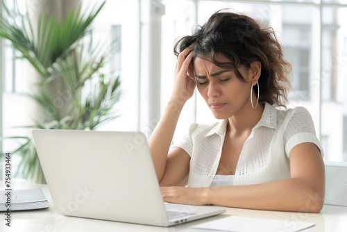 Young beautiful womanhad a strong headache. Sitting at a desk with a laptop.