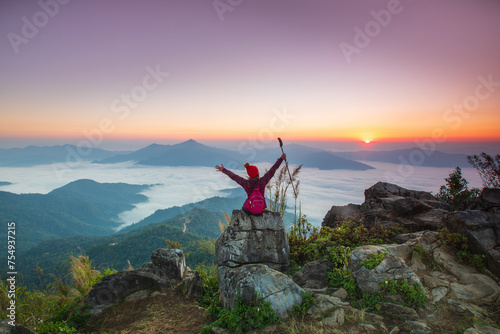 Young woman in red jacket hiking on the high mountain, Doi Pha Tang, Chiang Rai province, border of Thailand and Laos.