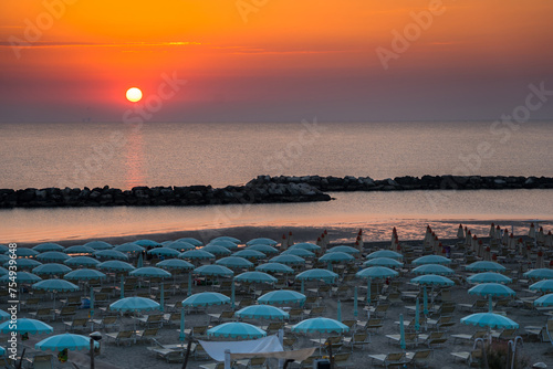 Beautiful sunrise on Rimini beach with umbrellas