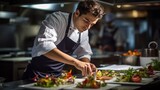Chef in hotel or restaurant kitchen preparing meal vegetable salad with goat cheese and decorates the food with his hands.