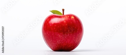 A single red apple with a green leaf, a seedless fruit, is a superfood and a natural food. It is a produce that can be considered a local food and an accessory fruit, showcased on a white background