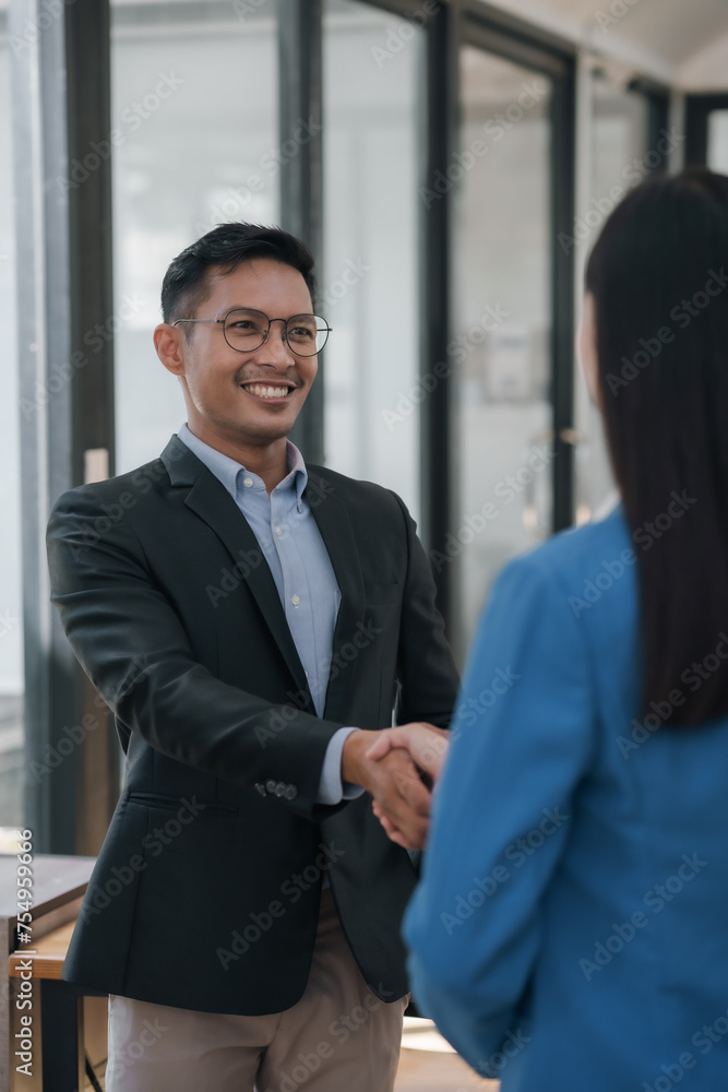 Two professional asian business colleagues engaging in a firm handshake at meeting. Two professional asian business colleagues engaging in a firm handshake at meeting.