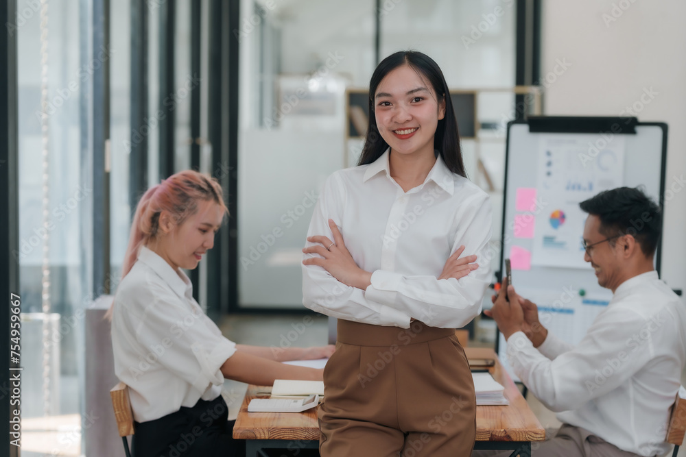 Obraz premium Confident young Asian business woman sitting with arms crossed smiling looking at camera in the office.