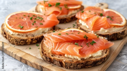 a wooden cutting board topped with slices of bread covered in cheese and salmon on top of slices of grapefruit. photo