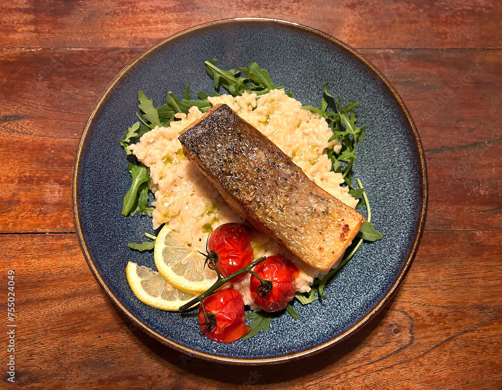 Seared salmon steak with lemon risotto, braised cherry tomatoes, arugula and lemon. Seared salmon steak with lemon risotto, braised cherry tomatoes, arugula and lemon.