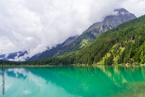 Serene Antholzer See Lake Surrounded by Lush Green Mountains under a Cloudy Sky, South Tyrol, Italy