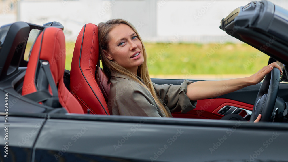 Confident business woman enjoying the new ride in a sleek convertible car Confident business woman enjoying the new ride in a sleek convertible car