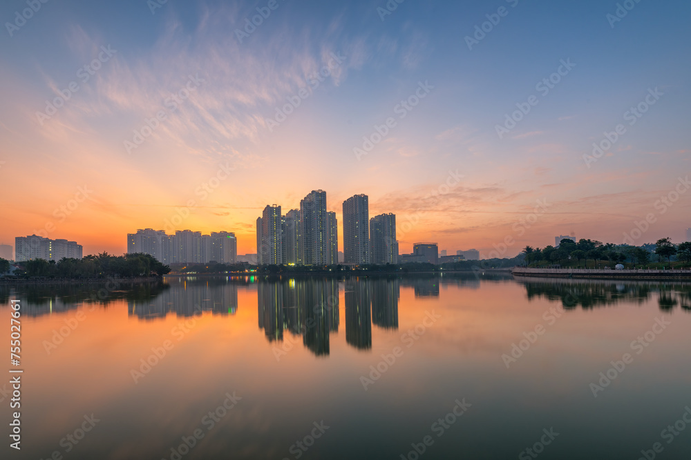 Buildings with reflections on lake at sunset at An Binh City, Hanoi.