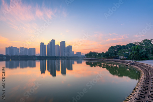 Buildings with reflections on lake at sunset at An Binh City, Hanoi.