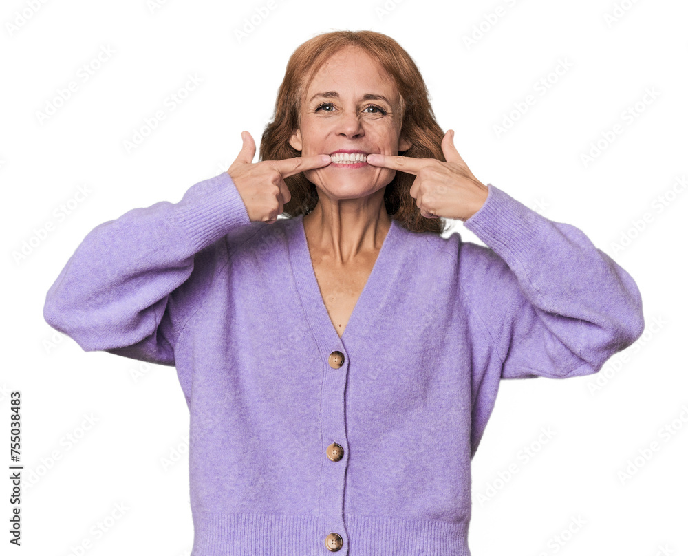 Redhead mid-aged Caucasian woman in studio smiles, pointing fingers at mouth. Redhead mid-aged Caucasian woman in studio smiles, pointing fingers at mouth.