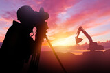 Silhouette surveyor. Man with geodetic instrument at sunset. Surveyor works at construction site. Engineer with equipment for geodetic research. Surveyor engineer near excavator. Guy with theodolite