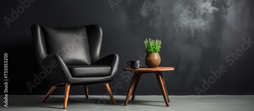 A cosy armchair and a minimalistic coffee table are placed against a black wall. On the table, there is a potted plant, creating a simple and elegant interior design. photo
