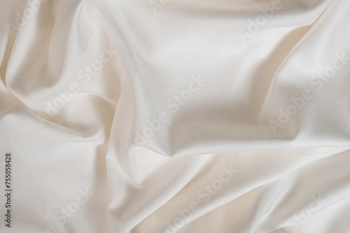 Waves and patterns of crumpled natural satin white milk color fabric.