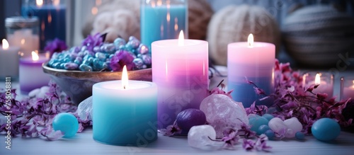 A closeup view of a white table adorned with numerous lit candles in shades of purple and blue  creating a warm and inviting ambiance.