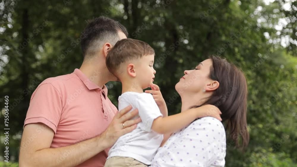 A man and a woman have a happy moment in the park, hugging each other and their child. Happy family in the park A man and a woman have a happy moment in the park, hugging each other and their child. Happy family in the park