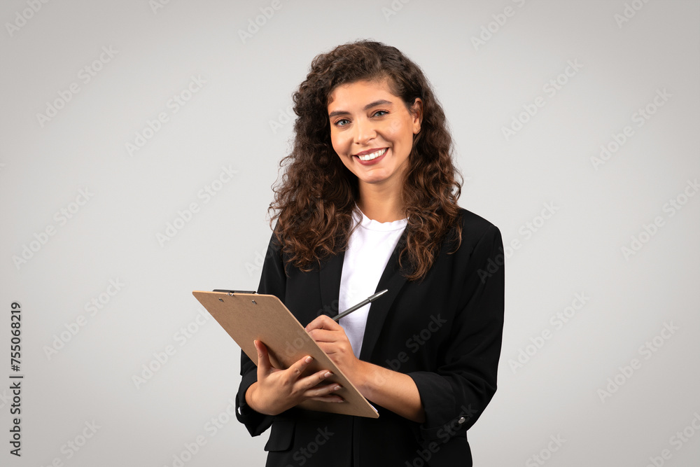 Confident young businesswoman writing on clipboard Confident young businesswoman writing on clipboard