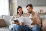 Confused spouses reviewing documents with tablet