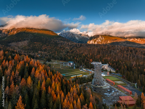 Strbske Pleso, Slovakia - Aerial view of the Strbske Lake area with autumn foliage, sightseeing tower and the High Tatras mountains at background on an autumn afternoon at sunset with warm sunlight