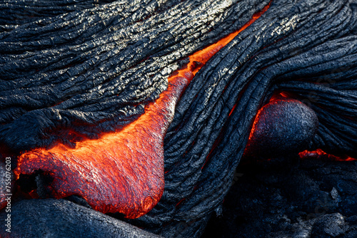 Red hot glowing lava flowing from a volcano in Hawaii photo