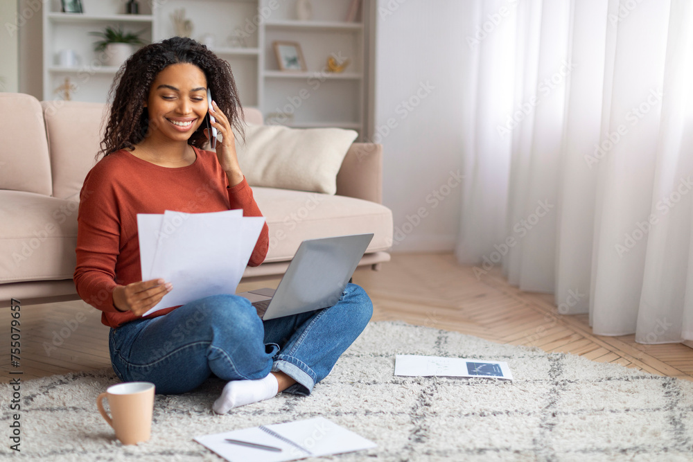 Remote Career. Black Woman Working At Home With Laptop, Cellphone And Papers Remote Career. Black Woman Working At Home With Laptop, Cellphone And Papers