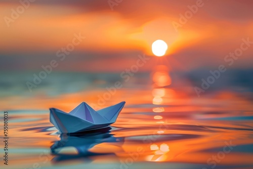 A paper boat floats on the calm surface of a body of water during sunset.