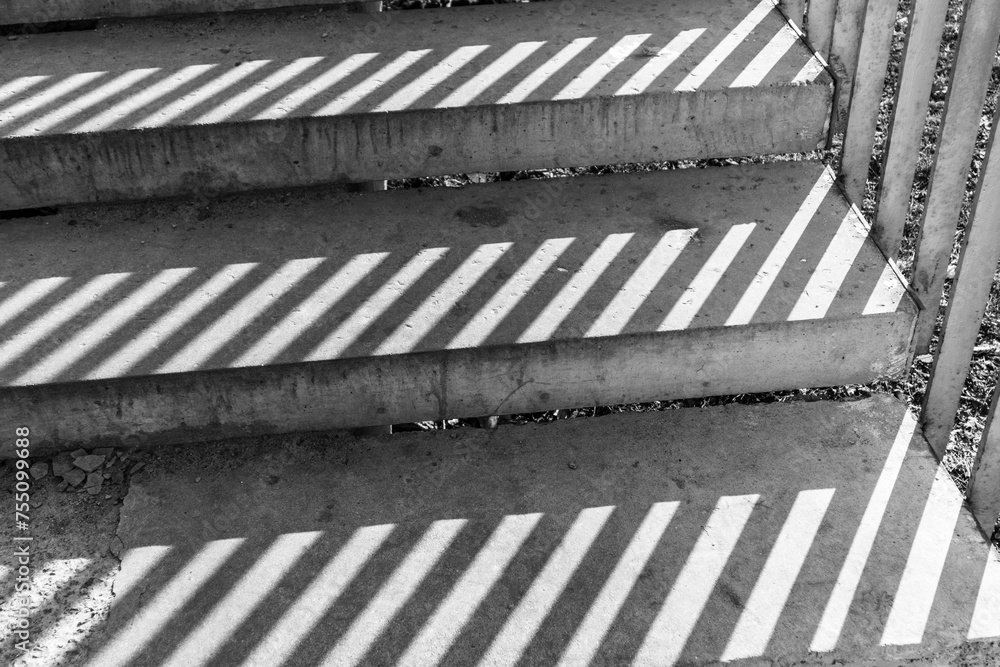 Shadow from iron railings on the concrete staircase. Striped shadow on gray steps Shadow from iron railings on the concrete staircase. Striped shadow on gray steps
