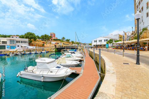Boats line the picturesque marina port harbor full of shops and sidewalk cafes at the seaside town of Ciutadella de Menorca, on the Balearic island of Menorca in the Mediterranean Sea. 