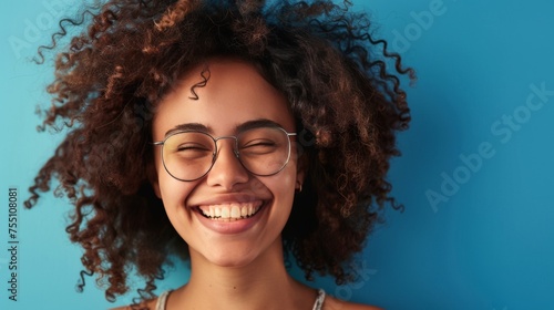 Portrait of a Young Afro Woman Wearing Glasses against a Blue Background