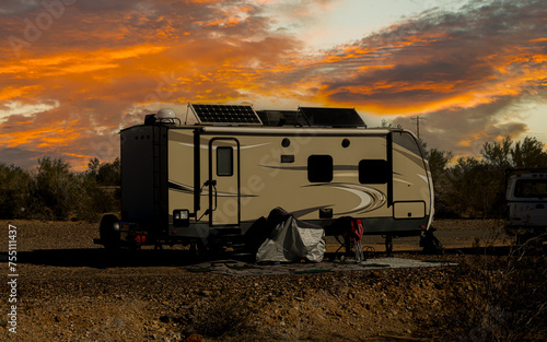 Rv trailer parked in open land area on self power with solar panels on roof 