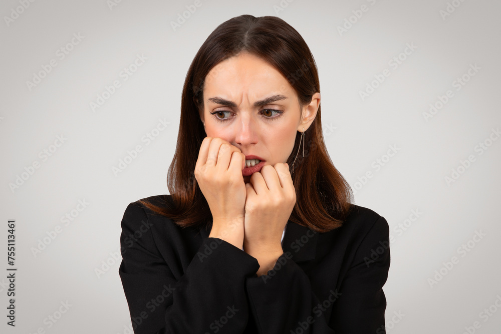 Anxious businesswoman biting her nails with a look of deep concern on her face Anxious businesswoman biting her nails with a look of deep concern on her face