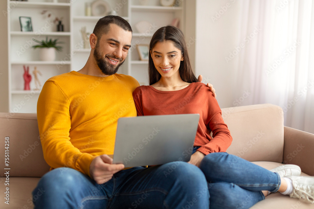Technologies For Leisure. Happy Young Couple Using Laptop Together At Home