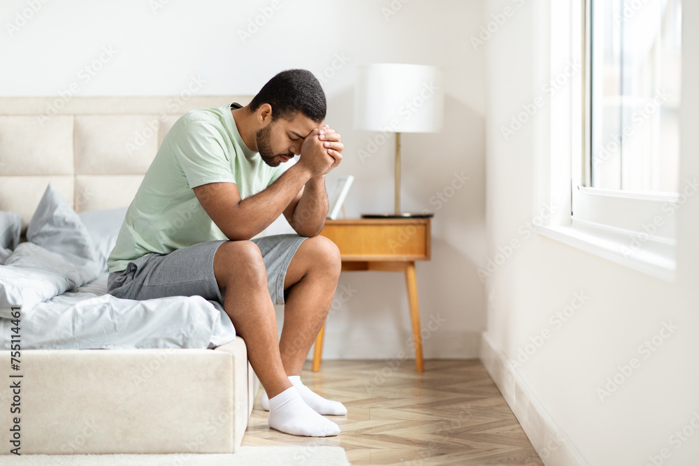 Unhappy african american guy suffering from loneliness, bedroom interior Unhappy african american guy suffering from loneliness, bedroom interior