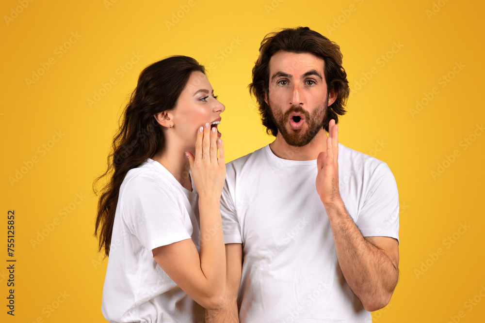 Surprised bearded man with wide eyes and an open mouth holds his hands up while a woman whispers into his ear Surprised bearded man with wide eyes and an open mouth holds his hands up while a woman whispers into his ear