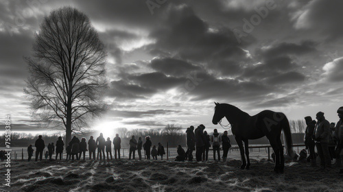a black and white photo of a group of people standing in front of a tree with a horse in the foreground. photo