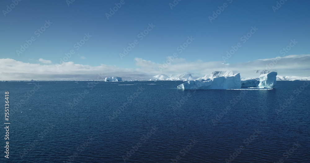 Cold Antarctica blue water ocean drone flight. Icebergs from melted glaciers floating in sunny day. Polar summer scene. Ecology, melting ice, climate change, global warming concept. Nature background