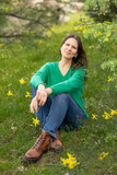 A middle-aged woman relaxes in a park with daffodils in bloom