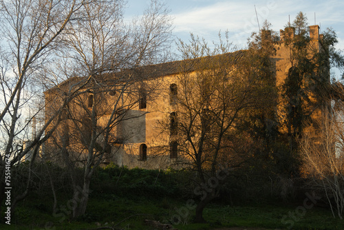 Vista con el sol del atardecer de un edificio antiguo que se usaba como molino para hacer aceite a orillas del río Guadalquivir, Andalucía