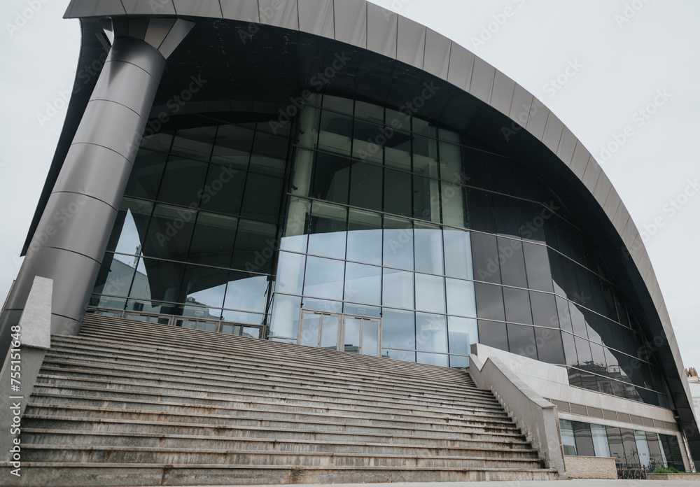 Fototapeta premium Contemporary architecture of a glass office building with stairs, perfect for business and corporate themes.