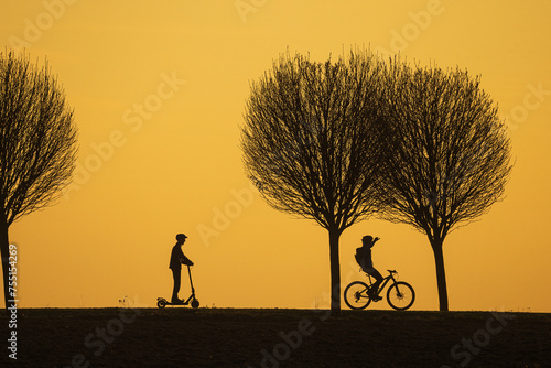 black silhouettes of people riding bicycles against the colourful background of the setting sun