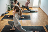 A small group of yoga students practices poses in a cozy studio, guided by their instructor's calm instructions.