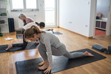 A small group of yoga students practices poses in a cozy studio, guided by their instructor's calm instructions.