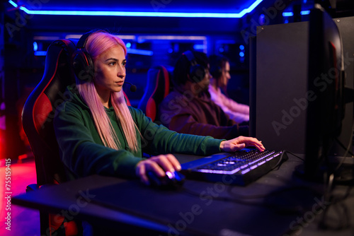 Cybersport woman gamer with pink hair playing a video game with her team