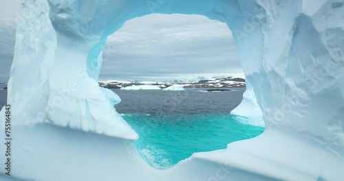 Huge hole in melting iceberg in Antarctic ocean close up. Flight inside frozen glacier cave arch window drifting blue cold water. Arctic winter landscape, global warming problem. Polar climate change
