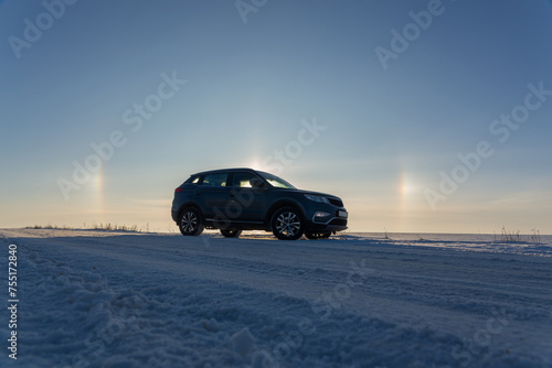 Winter landscape with car and circular halo phenomena around the sun