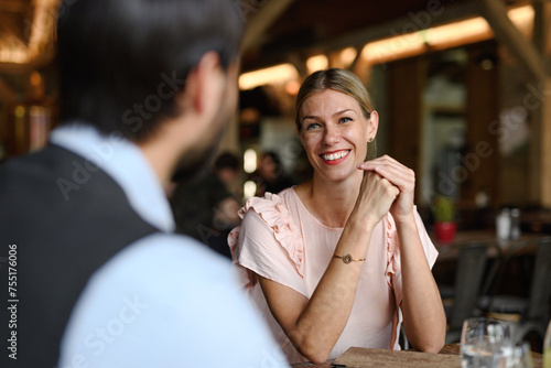 Happy loving couple at date in restaurant. Husband and wife sitting at table  laughing  having lunch in modern cafe.