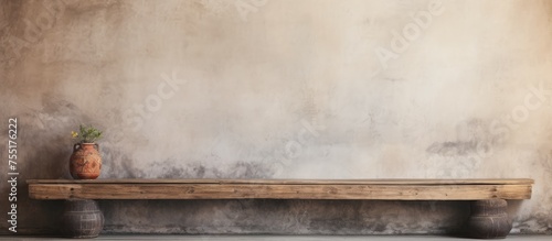 A weathered wooden bench is placed in front of a textured cement wall, creating a simple yet rustic look in a loft-style space. The combination of materials adds character to the setting.